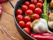 A vivid display of fresh Mediterranean vegetables on a wooden table with a pan.